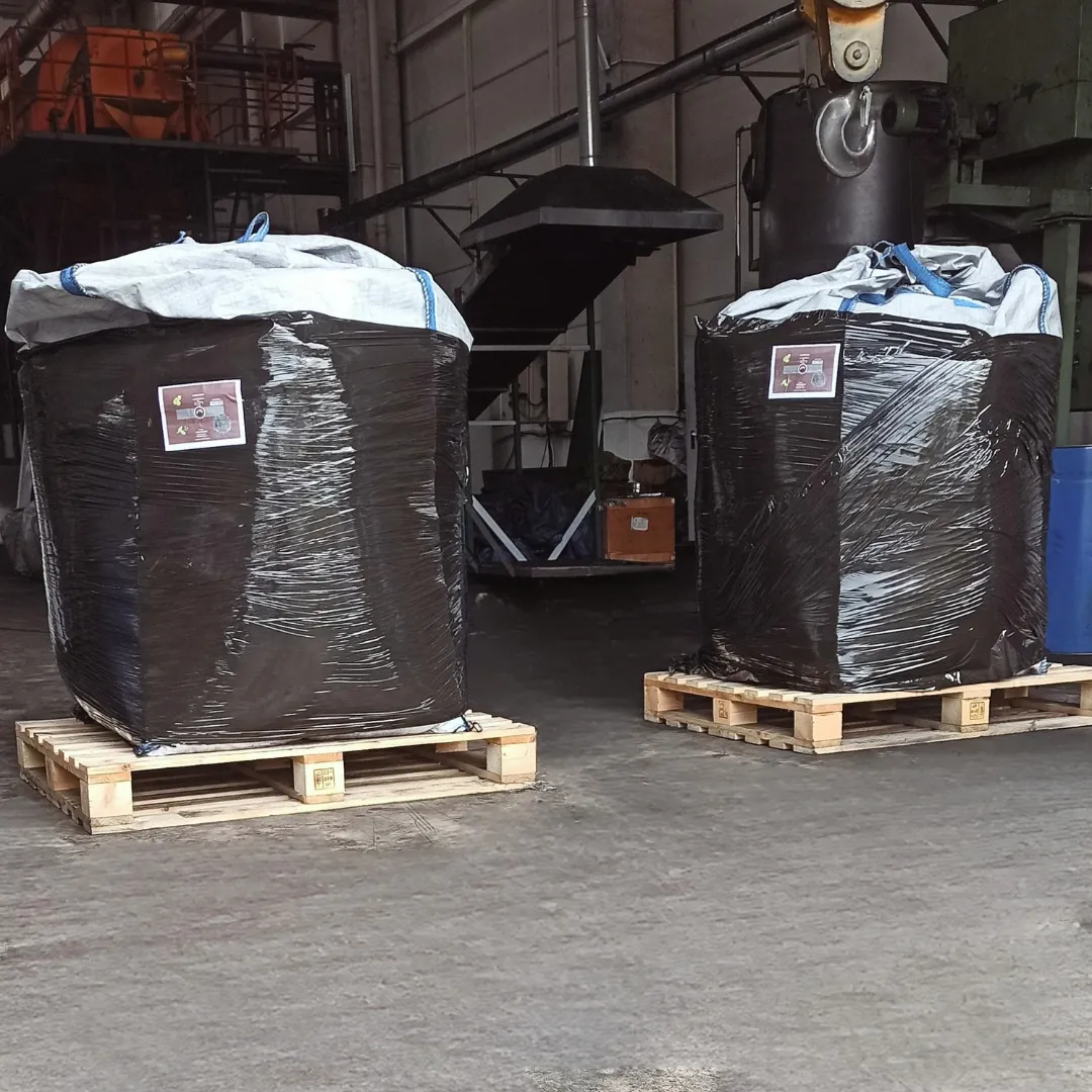 Shipment-ready big-bag activated carbon sacks wrapped in black film, on wooden pallets inside the facility